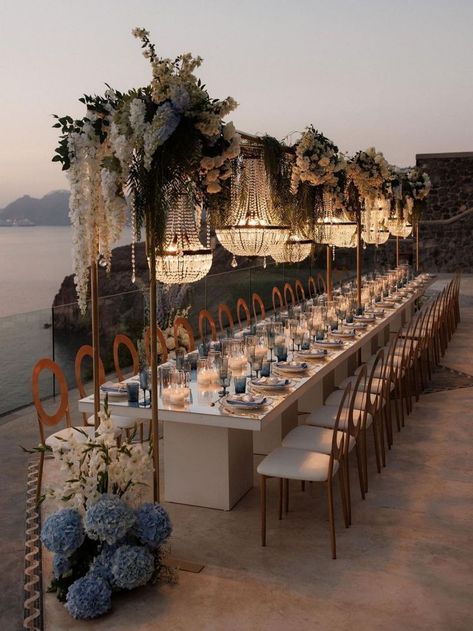 Elegant florals, crystal chandeliers & breathtaking views make this wedding reception unforgettable | wedding, wedding inspo, wedding planning, wedding reception decor, wedding reception ideas, wedding reception decor, intimate wedding, destination, wedding, Santorini, Santorini wedding, luxury wedding reception, wedding tablescapes, wedding table decor, wedding flowers, wedding table centerpieces, summer wedding, blue wedding, something blue wedding #weddingreception #summerwedding #Santorini Outdoor Wedding With Chandelier, Greek Wedding Table Decor, Wedding Arab, Villa Wedding Reception, Engagement Setup, Greek Island Wedding, Greek Islands Wedding, Dream Wedding Reception, Wedding In Greece