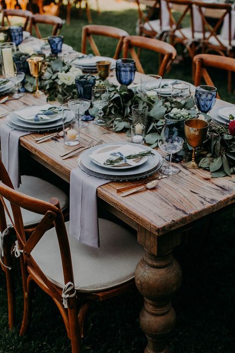 This rustic tablescape features blue decor, greenery, and gold accents | Image by Emily Magers Rustic Tablescape, Wedding Planning Notebook, Christmas Wedding Gifts, Outdoor Dinner, Dusty Blue Weddings, Wedding Reception Tables, Long Table, Wedding Tablescapes, Wedding Table Centerpieces