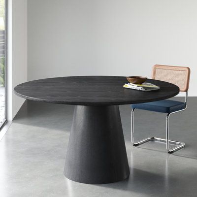 This modern round dining table brings a touch of sophistication to your dining space. With a pedestal base made from solid wood and an ebony black finish, this table adds a contemporary flair to your room. The top is crafted from engineered wood, showcasing natural wood grain color variation for a unique look. Seating up to six guests, this table is perfect for intimate gatherings or family dinners. Weighing in at 100 lbs. it offers stability without compromising on style. | Wade Logan Boudot Pe 48 Inch Round Table, Mid Century Modern Round Dining Table, Modern Round Dining Room Table, Modern Oval Dining Table, Black Round Dining Table, Modern Round Dining Table, Round Dining Table Modern, Round Dining Room Table, Dining Table Black