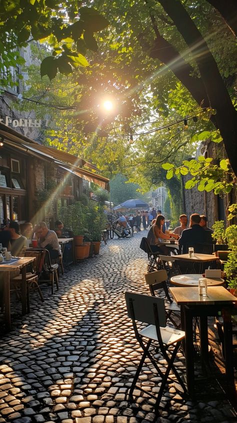 Sunlit Cobblestone Alley: A serene sunlit alleyway with people enjoying outdoor dining on a beautiful cobblestone street. #sunlight #alley #cobblestone #dining #outdoor #trees #city #cafes #aiart #aiphoto #stockcake https://ayr.app/l/ic7K City Trees Street, Italian Cobblestone Street, Alleyway Restaurant, Parisian Patio, Urban Hiking, Candela Obscura, Pretty City, Cobblestone Street, Seaside City