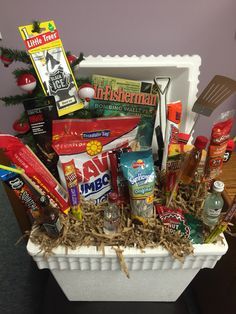 Male gift basket. A great idea for the outdoorsman!   Styrofoam cooler, fishing magazine, potato chips, meat sticks, candy bars, sunflower seeds, mini liquor bottles, grilling utensils, fishing bobbers And assorted tackle. Gone Fishing Gift Basket Ideas, Fishing Gift Basket Ideas Diy, Fathers Day Fishing Gift Basket, Father's Day Basket Ideas, Fisherman Gift Basket, Fishing Easter Basket For Men, Male Gift Baskets, Father’s Day Gift Baskets, Guy Gift Baskets