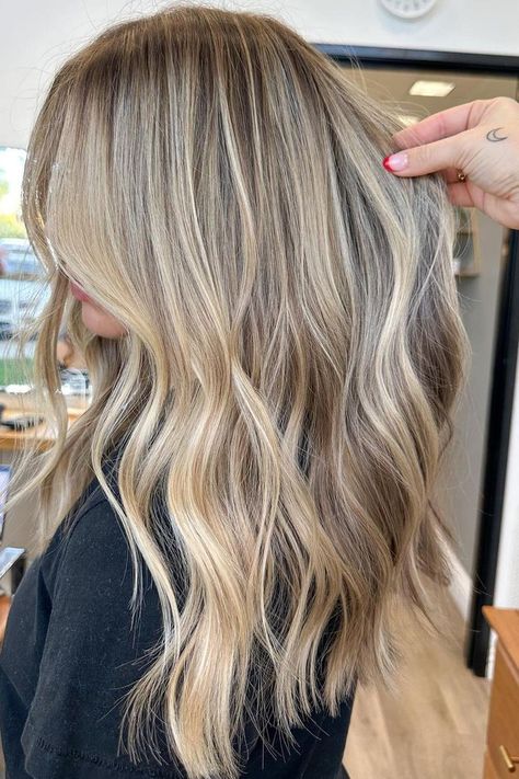 Sunkissed balayage on long layered hair creates a seamless transition from ashy brown roots to icy blonde ends, giving this look natural depth and movement. The soft waves enhance the multi-dimensional colors, ideal for adding volume to fine hair. It's a beautiful blend that works great for various occasions.  // Photo Credit: Instagram @hairby_savss Root Melt Blonde Highlights, Creamy Blonde Balayage Dark Roots, Blonde And Brunette Highlights, Blonde Brown Lowlights, California Blonde Highlights, Bright Blonde Balayage On Brown Hair, Winter Lowlights For Blondes, Dirty Blonde Hair With Dimension, End Of Summer Hair Color