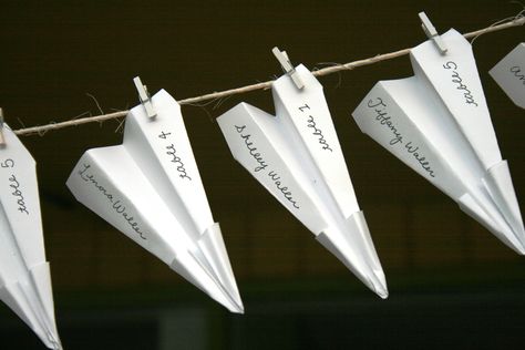 Paper Airplane name tags attached on a string with tiny clothes pins.  Groom is a pilot Wedding Paper Planes, Paper Airplane Party Decoration, Airplane Event Theme, Paper Airplane Place Cards, Airplane Seating Chart Wedding, Wedding Table Placement, Origami Plane, Jamaican Wedding, Airplane Theme