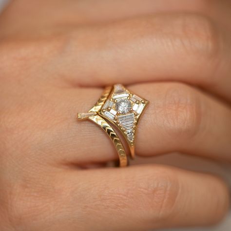 The star shaped engagement ring is complemented by an intricately detailed chevron wedding ring. Radiating out in a gradient web are shimmering diamond baguettes that surround the round center stone. The design is inspired by the elegant and glamorous art deco style, characterized by smooth lines, geometric shapes and streamlined forms. MATERIALS: 18k solid gold | assemblage of a gradient in size needle baguette-cut diamonds (extra long!) Diamonds total carat weight: ~1.12 carat Diamonds paramet Two Band Wedding Ring Set, Dream Engagement Rings Vintage Inspired, Art Decor Rings Engagement, Gold And Opal Engagement Ring, Unique Engagement And Wedding Ring Sets, Art Deco Moissanite Engagement Ring, Wedding Ring Art Deco, Art Deco Stacked Wedding Rings, Vintage Engagement Ring Stack