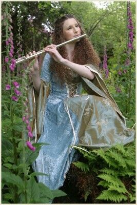 Lovely Renaissance scene of a young woman in long blue dress playing her flute while sitting on a mossy log among the ferns and wildflowers in the forest woods. -DdO:) - http://www.pinterest.com/DianaDeeOsborne/peaceful-people - Pin photo via Jenny Conley Person Playing The Flute Reference, Flute Instrument Aesthetic, Flute Holding Pose, Person Playing Flute, Flute Player Aesthetic, Playing Flute Pose Reference, Flute Pose Reference, Flute Reference, Drape Reference