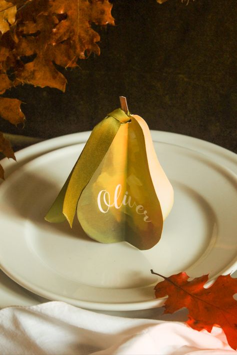 oil painting come to life.  3D paper pear features print that looks like an oil painting.  Appears to have a texture same as an oil painting but is a #D cut out.  Embellished with a beautiful satin green ribbon that looks like a per leaf.  Dark academia aesthetic, cottage core, very old world christmas feel. Pear Table Setting, Pear Name Cards, Pear Themed Party, Personalized Table Setting, Diy Place Settings, Place Card Ideas, Dinner Party Table Settings, Tabletop Design, Thanksgiving Place Cards