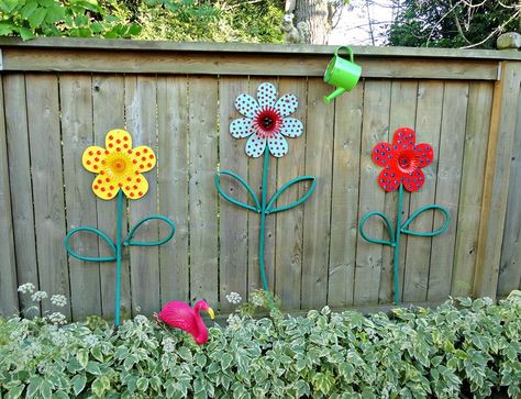 use old hoses and paint some wooden flowers to make these cute garden flowers.  40 Surprisingly Awesome Dollar Store Crafts Backyard Flowers, Pool Fashion, Fence Art, Outdoor Crafts, School Garden, Fence Decor, Creative Gardening, Wooden Fence, Wooden Flowers