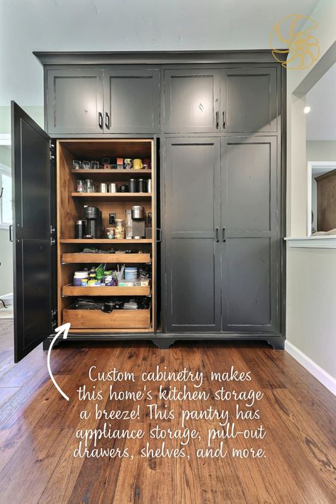 A floor-to-ceiling custom pantry with black cabinets and natural wood interior. The large pantry has French hideaway doors, which are seen in action as half of the pantry is open in the image. Inside the cabinet are two coffee machines, pull-out drawers, and plenty of shelving. The image has text that reads, "Custom cabinetry makes this home's kitchen storage a breeze! This pantry has appliance storage, pull-out drawers, shelves, and more." with an arrow pointing to the interior of the pantry. Pantry Wall Ideas Built Ins, Standalone Pantry, Built In Pantry Cabinet Wall, Farmhouse Kitchen Aesthetic, Lakehouse Kitchen, Whole House Remodel, Island Seating, Kitchen 2024, Built In Pantry