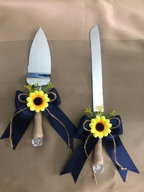 "This cake knife and server set is perfect for wedding, anniversary, bridal/baby shower or any special occasion.  The handles are covered with burlap for a rustic look and decorated with navy ribbon bow, twine bow, greenery & sunflower. The stainless steel cake serving set includes one 12\" long cake knife and one 10\" long X 2\" wide  cake server. To clean, hand wash only." Navy Blue And Yellow Wedding Cake, Navy And Sunflowers Wedding, Navy And Sunflower Wedding Decorations, Navy Blue And Sunflower Wedding Wedding Table Decor, Sunflower And Blue Rose Wedding, Navy Blue And Sunflower Wedding Theme, Navy Blue And Sunflower Wedding Ideas, Royal Blue And Sunflower Wedding, Dusty Blue And Sunflower Wedding