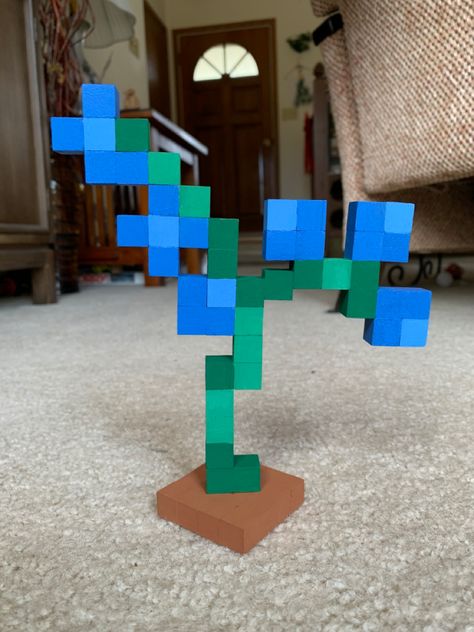 Minecraft blue orchid flower made of small wooden blocks painted. Green stem with 6 blue flowers. Terracotta brown square base at the bottom. Painted Minecraft Blocks, Minecraft Flower Out Of Blocks, Minecraft Blue Orchid Flower, Minecraft Block Painting, Blue Orchids Minecraft, Small Diy Wood Gifts, Wood Block Minecraft Flower, Wood Block Pixel Art, Minecraft Block Flowers Diy