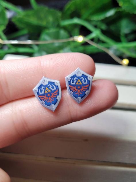 10 mm Hylain shield stud earrings, made with plastic and resin. Video game themed earrings make a great gift! Zelda Gifts, Hylian Shield, Drip Drip, Idee Cosplay, Birthday Stuff, Zelda Art, Funky Jewelry, Birthday Wishlist, Beauty Stuff