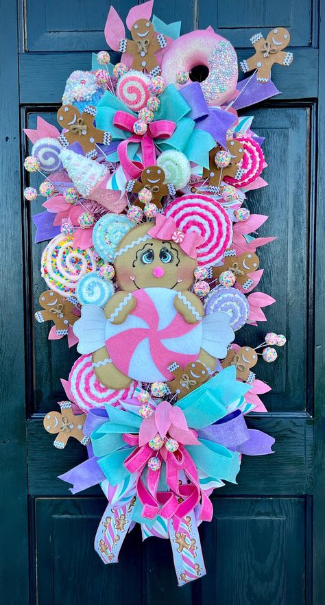 Add a touch of sweetness to your holiday decor with this delightful Candy Land Themed Gingerbread Door Swag! Perfect for welcoming guests with a festive flair, this handcrafted swag features a charming gingerbread figure holding a pink candy cane, surrounded by an array of colorful candies, cupcakes and ribbons. - Handcrafted with Love:  Each element of this door swag is carefully crafted and assembled by hand, ensuring a unique and high-quality piece. - *Vibrant and Festive: The swag is adorned Candy Land Garland Diy, Christmas Candy Door Decorations, Gingerbread Swag Wreath, Vibrant Christmas Decor, Pink Candy Christmas Decorations, Candy Land Wreath, Diy Candy Land Decorations, Pink Gingerbread Christmas Decor, Gingerbread Themed Christmas Decor