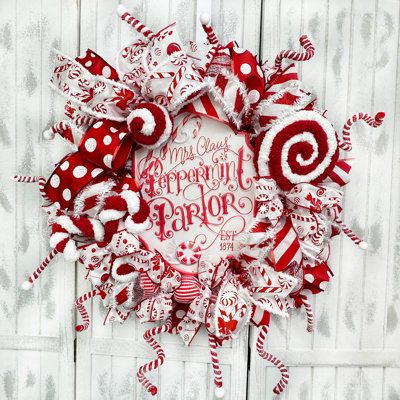 Welcome your family and friends this holiday season with this adorable Christmas wreath featuring a scalloped metal sign that says “Mrs Claus Peppermint Parlour”.The wreath is made with white and red weather resistant deco mesh and is decorated with a large handmade peppermint lollipop, candy decoration, candy canes and a peppermint ornament adorning the bow, giving the wreath a perfect finishing touch! Ribbon that complements the decoration is spread around the perimeter. | The Holiday Aisle® M Peppermint Decorations, Peppermint Christmas Decorations, Peppermint Ornament, Snowflake Wreath, Peppermint Christmas, Deco Mesh Christmas Wreaths, Candy Cane Wreath, Candy Decorations, Christmas Wreaths For Front Door