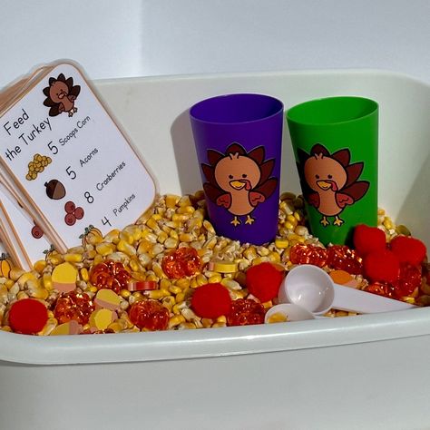 "Feed some hungry turkeys with this thanksgiving inspired sensory bin. Use the direction card to add what you need for each turkey dinner, then add it to the turkey cup. Work on number identification and counting skills as you feed the turkey. Includes enough for two children to play! Perfect for a classroom or home sensory bin.  Each set includes: 2 lbs of large kernel corn  15 pumpkins 15 acorns 15 pom pom \"cranberries\" 2 Turkey cups  2 scoops 16 'recipe' cards" Thanksgiving Sensory Table Preschool, Turkey Sensory Bin Preschool, Corn Kernel Sensory Bin, Feed The Turkey Sensory Bin, Sensory Bin Thanksgiving, Thanksgiving Sensory Play, November Sensory Table, Thanksgiving Sensory Bin Toddlers, Feed The Turkey Activity