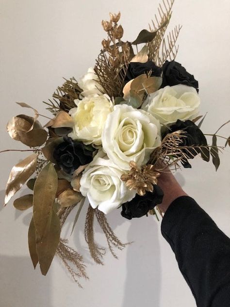 If your theme is gold and you are not superstitious about black, then this is a gorgeous, simple unstructured yet round bouquet for you.  This bouquet is high end quality  black roses, cream latex David Austin, realistic roses, dried and sprayed gum leaves, grevillea &  sprayed in a gorgeous gold.  This listing is for 1 Bridal bouquet and 1 Groom button hole. See one of our beautiful Brides, Jayme who ordered this gorgeous creation.  I can custom order to suit, simply send me a message. For over Gold Wedding Bouquets, Gold Wedding Flowers, Black Bouquet, Gold Bouquet, Black And White Wedding Theme, Round Bouquet, Black Gold Wedding, White Wedding Theme, Gold Wedding Theme