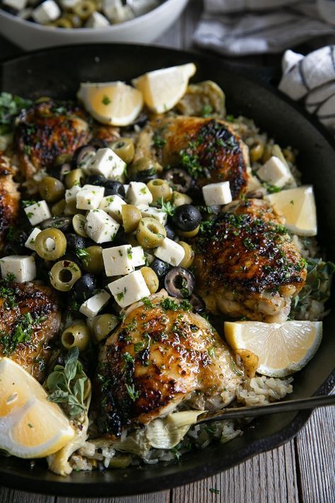 Close up image of chicken thigh cooked and covered with fresh herbs sitting in a skillet with cooked lemon rice and mixed olives and feta cheese. Chicken Olives, Olive Chicken, Herbed Chicken, Chicken Lemon, Rice Bake, Olive Recipes, Rice Chicken, Cooked Meal, Lemon Rice