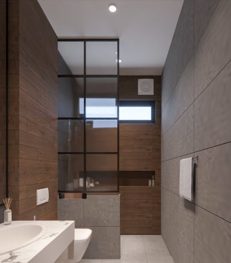 This stunning small bathroom design has a very modern yet minimalist vibe. A tall mirror is mounted on the wall and is accompanied by a small vanity. The shower area has been cleverly separated from the rest of the space by a glass partition, resting on a small wall, acting as a barrier. The shower area features a narrow yet wide niche, which is perfect for storing shower products, adding to the functionality of the space. Shower Area Glass Partition, Bathroom Shower Partition Wall, Bathroom Glass Partition Ideas, Narrow Bathroom Design Ideas, Bathroom Partition Glass Design, Small Bathroom Partition Ideas, Small Toilet Design Modern Minimalist, Wash Room Ideas Bathroom, Washroom Glass Partition