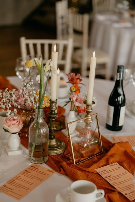 Round tables for wedding reception with orange table runners and orange wedding menus with white candles, glass vases of flowers and a clear gold photo frame table name Photo Frame Table, Round Table Centerpieces, Round Wedding Tables, Round Table Decor, Yellow Wedding Flowers, Ireland Wedding, Table Runners Wedding, Orange Wedding, Wedding Table Decorations