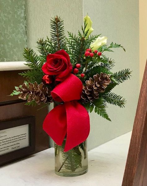 Clear vase with artificial pine greenery. Decorated with a rose, berries, pinecones and ribbon. Your choice of red, burgundy or white rose. Red & white rose comes with red ribbons. Burgundy rose comes with burgundy ribbon. All sales final. Christmas Vase Arrangements, Christmas Vase Filler Ideas, Christmas Flower Arrangements Ideas, Christmas Floral Arrangements Diy, Christmas Gala, January Decor, Golf Christmas, Winter Floral Arrangements, Burgundy Ribbon