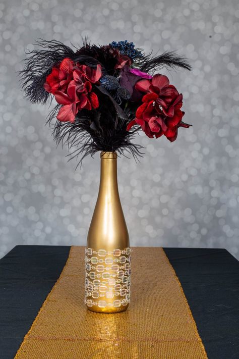 Made with ostrich feathers, wine bottles, faux flowers, champagne glasses, martini glasses and candles, these DIY Gatsby party centerpieces are easy to make and look beautiful. #entertainingdiva #centerpieces #wedding #gatsbyparty Gatsby Party Centerpieces, Diy Gatsby Party, Great Gatsby Centerpieces, Gatsby Centerpieces, 20s Party Decor, Champagne Glass Tower, Great Gatsby Party Decorations, 20s Party Decorations, Ostrich Feather Centerpieces