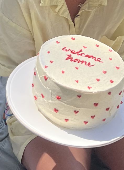 Layered cake with buttercream frosting and red mini hearts with the words “welcome home” written in cursive writing with red icing piped on top of a tall white cake. Welcome Cake For Husband, Housewarming Party Cake, House Warming Aesthetic, No Contact Cake, House Warming Cake Design, Welcome Home Cake Design, Welcome Back Cake Ideas, Frosting Cake Ideas, New Home Cake Ideas