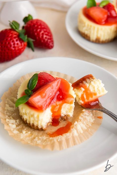 fork taking bite of mini cheesecake with strawberry sauce on paper muffin liner. Chunky Monkey Brownies, Easy Mini Cheesecakes, Graham Cracker Crust Cheesecake, Strawberries And Whipped Cream, Mini Cheesecakes Easy, Strawberry Sauce, Mini Cheesecakes, Graham Cracker Crust, Strawberry Cheesecake