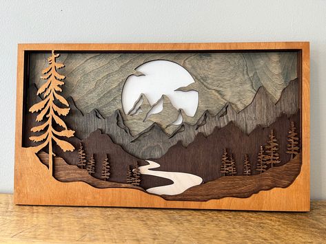 Introducing our Rustic Wood Layered Mountain Scene, a stunning laser cut artwork that brings nature's beauty to your home. Each piece is carefully stained, resulting in a unique creation every time. Bring the mountains home. Order your Rustic Wood Layered Mountain Scene now and embrace nature's wonder. Cnc Projects Ideas, Epoxy Pictures, Layered Wood Art, Tiny Interior, Cardboard Art Sculpture, 3d Mountain, Mountain Wood Art, Mountain Wood Wall Art, Rustic Wood Wall Art