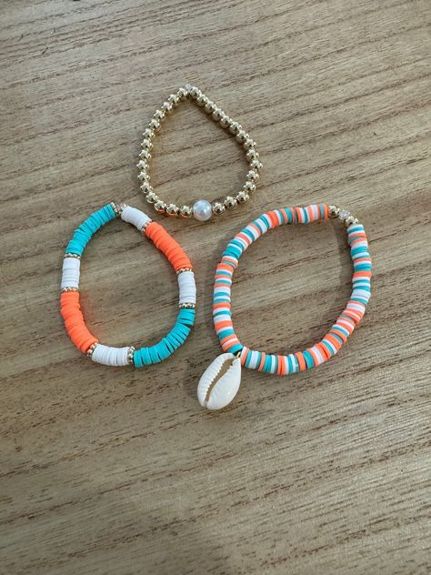 This Summer Beach Bracelet Set is made of clay beads in orange, blue, and white, a cowrie shell, a pearl bead, and lots of gold accents.  These bracelets are made-to-order, and may take up to three business days to ship.  Please specify size in variations. To get your wrist size, wrap a piece of string comfortably around your wrist, measure the string flat against a ruler, and add a half inch (or use size chart below). This is your wrist size. If size is not specified, there is no guarantee of fit.  (This is an approximate guide. Measure wrist for most accurate results.) Petite: 6-6.5in. Small: 7-7.5in. Medium: 7.5-8in. (7.5 is the most popular) Large: 8-8.5in Price is for one set of three bracelets. Care: Do not expose to direct sunlight or water. We have taken extra care to ensure that y Cute Clay Bead Anklets, Matching Best Friend Clay Bead Bracelets, Bracelet Ideas Flat Beads, Ombre Beaded Bracelet, Clay Bead Bracelet Ideas Ocean, How To Put Shells On A Bracelet, Hawaii Clay Bead Bracelets, Pearl Clay Bead Bracelet Ideas, Trendy Bracelet Ideas