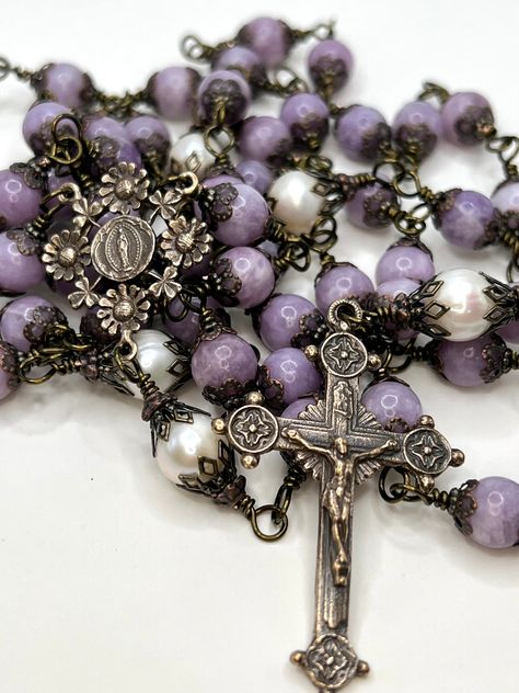 "FIVE DECADE ROSARY FEATURING Mary, Souvenir of Lourdes, Flowers Vintage Replica Bronze Centerpiece * 10mm Natural Pearls Pater Beads * 8mm Lavender Mica (Lepidolite) Maria Beads * Brass Bead Caps * 2\" Vintage Replica Bronze Crucifix Circle Points * 1 1/4\"  Vintage Replica Bronze Mary, Souvenir of Lourdes, Flowers Center * Length 33\" Each bead is individually wire wrapped and should never come apart. It will drape beautifully around your hand." Beautiful Rosaries, Flower Rosary, Bronze Centerpiece, Rosary Making, Vintage Rosary, Flowers Lavender, Decade Rosary, Pearl Rosary, Praying The Rosary