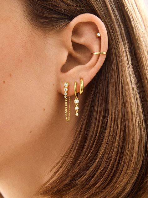 Introducing our Jenelle 18k Gold Earring Set – three times the charm in one stylish set. Choose between dainty drop earrings, delicate huggies with a shimmering drop accent, and a timeless huggie. Wear them all together or mix and match depending on your everyday mood. Either way, you’re set for years of style, thanks to its 18K gold plated sterling silver and Cubic Zirconia stones. Stack Hoop Earrings, Stack Earring Ideas, Dainty Earring Set, Triples And Cartilage Ear Piercing, Triple Stack Earrings, Earring Stack 3, Doubles And Cartilage Piercing, Hairstyles For Big Earrings, Earrings Gold Stack