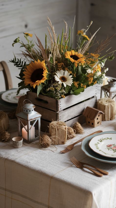 A charming farmhouse-inspired table centerpiece featuring an array of rustic elements. At the center is a wooden crate filled with freshly picked seasonal flowers, including sunflowers, daisies, and wild grasses. Check out this decorative wooden crate link in the pin. I am an affiliate marketer, so I promote products I think users will find helpful, for a commission, at no extra cost to you. Follow for more product ideas and inspiration! #decorative #farmhouse #farhmouseideas #woodencrate #DIY Rustic Farm Centerpieces, Wooden Crate Ideas, Farm Table Centerpiece, Round Table Centerpiece, Head Table Wedding Decorations, Wedding Crates, Small Wooden Crates, Garden Center Displays, Backyard Party Decorations