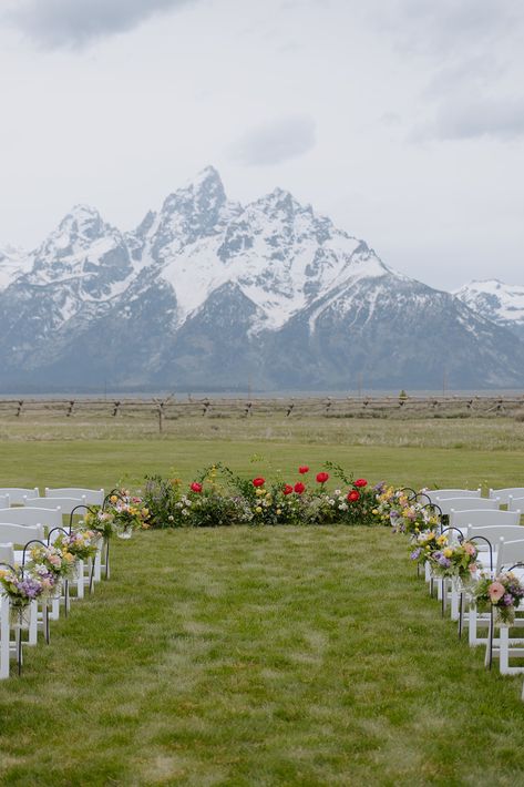 The Grand Teton Mountains lay behind a wedding ceremony with a floral ground installation and aisle of spring flowers. Simple Colorado Wedding, Montana Outdoor Wedding, Jackson Hole Wyoming Wedding Venues, Colorado Wedding Ceremony, Wedding In Glacier National Park, Wedding In The Mountains Colorado, Wyoming Wedding Jackson Hole, Elope Jackson Hole, Banff National Park Elopement