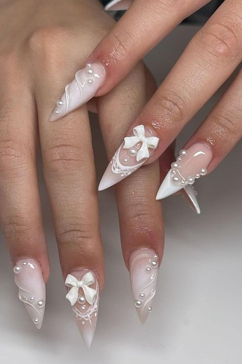 Discover the epitome of elegance with these exquisite white stiletto nails adorned with pearl embellishments and delicate 3D bows. The soft ombre transition from pale pink to white, coupled with intricate lace designs, creates a stunningly feminine look. Click through to explore the entire collection and embrace unmatched sophistication. // Photo Credit: Instagram @nailsbyalyk Chic Nail Art, May Nails, White Nail, Stick On Nails, Chic Nails, Stiletto Nails, Wedding Nails, Trendy Nails, French Nails