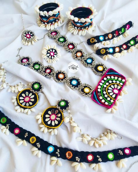 Are you an early bird who's planning to rock this navratri season with her pre-planned traditional look? If yes, checkout this beautiful Multicolored Jewellery Set with black base to match your Garba Vibes for this Navratri Season 🔥 This beautiful ethnic jewellery set is adorned with lots of Cowrie shells and mirrors to give it a traditional Indian look😍 Items included: ❤️ Necklace ❤️ Jhumka with Sahara ❤️ Mang teeka ❤️ 6 Bangles Set ❤️ Ring ❤️ Anklets ❤️ Waist belt This set can b... Navratri Jwellery Set, Navratri Set Design, Garba Jewellery Diy, Navratri Special Jewellery, Handmade Navratri Jewellery, Gujrati Jewellery, Mirror Belt For Navratri, Diy Navratri Jewellery, Navratri Bangles Handmade