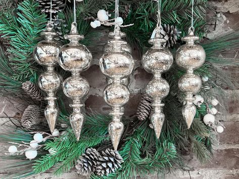 PRICES MAY VARY. Set of Six ornaments Each ornament measures 8.5-inch long Hand made & hand blown glass items, silvered on the inside of the glass as is traditional Silver color with subtle warm champagne tones for a vintage look Christmas Ornaments & Holiday Collectibles Made With only Quality Materials Keepsakes to delight for years to come! Mercury Glass Finial Christmas Ornaments Set of Six Silver Large Hanging Christmas Finials for Christmas Tree Decoration Holiday Décor. Box set of 6 Vinta Silver And Brown Christmas Tree, Victorian Holiday Decor, Christmas Finials, Raz Imports Christmas, Mercury Glass Christmas Tree, Glass Finial, Blue Christmas Decor, White Christmas Ornaments, Holiday Inspo