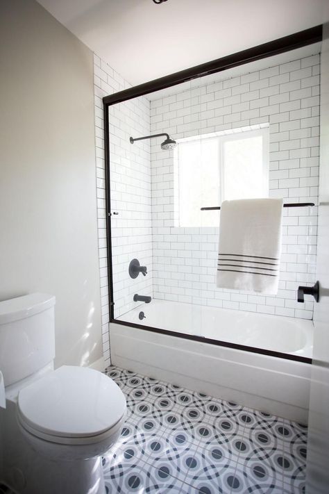 A black frame surrounding the glass shower door creates a bold color contrast and timeless combination with the white subway tile shower interior. A patterned black and white tile floor adds intrigue to simple style of the design. Black details pop for a crisp and attractive finish. White Subway Tile Shower, Subway Tile Showers, Trendy Door, White Tub, White Tile Floor, Doors Interior Modern, Tiles Floor, Bathroom Shower Tile, White Shower