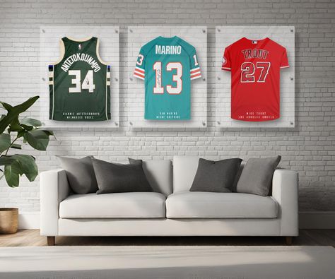 Protect your prized sports jersey with this custom personalized handmade acrylic display frame case. Each storage frame is handmade with 3 panels of ultra-clear 4mm thick high-grade acrylic that is UV-protecting and clear as glass. Each case is made up of 3 stacked acrylic panels. The center panel has a built-in hanger and provides the open spacing for the jersey to be protected from dust. The panels are stacked and locked in place with a series of 6 metal standoffs which then secure easily to y Framed Sports Jersey, Jersey In Frame, Framing A Jersey, Framed Basketball Jersey, Jersey Frame Ideas Display Case, Sport Memorabilia Display Wall, How To Display Jerseys On Wall, How To Frame A Jersey, Diy Jersey Display Case