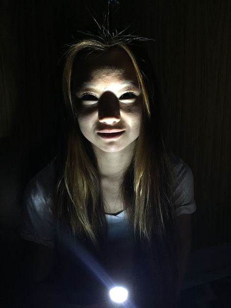 This photo represents unusual lighting. The light source is coming from the bottom instead of top left which makes it more interesting. This kind of lighting makes the overall picture look creepy. The shadows created on her face add drama. The lighting makes the picture have a creepy and intense meaning which is opposite of what it would be if the light source was from above. Lighting From Below Face, Light Source From Below Reference, Light Source From Above Reference, Bottom Light Source Reference, Above Head Lighting Reference, Under Lit Face, Reference Photos Dramatic Lighting, Creepy Lighting Reference, Light Coming From Below Reference