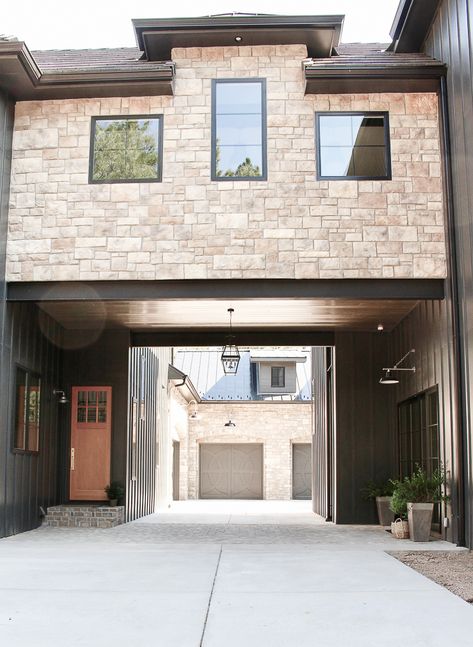 Modern Chateau Farmhouse exterior with stone, porte-cochere, and dark board and batten siding Farmhouse Exterior With Stone, Batten Siding Exterior, Board And Batten Siding Exterior, Dark Board And Batten, Modern Chateau, Modern Farmhouse Staircase, Cottage Shutters, Gooseneck Lighting, Black Metal Roof