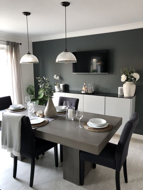 This solid concrete dining table still manages to look elegant in this sophisticated dining room, featuring dark walls and faux foliage, with industrial style pendant lights. The industrial touches are perfectly balanced with the more natural touches such as the curtains and blanket details. Concrete Table Decor, Dining Room Feature Wall, Grey Dining Tables, Concrete Dining Table, Grey Dining Room, Dinning Room Design, Esstisch Modern, Stone Dining Table, Small Kitchens