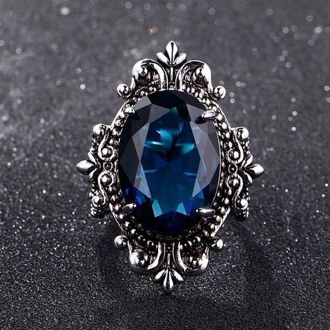 This gorgeous sterling silver ring is perfect for a person with a flare for vintage jewelry. The Blue Sapphire Peacock Vintage Ring features an oval blue sapphire as its centerpiece, encircled by small round white diamonds that catch the light gloriously and radiate life! From cornflower blue to velvety blue, there are multifarious shades of blue sapphire that gives it a silky tint. Characterized by the power of Shani or Saturn, Blue Sapphire displays violet to indigo and pale blue as well as da Sapphire Silver Ring, September Birthstone Rings, Blue Gems, Unisex Ring, Lovely Ring, Anniversary Party, Blue Sapphire Rings, Vintage Ring, Sapphire Gemstone