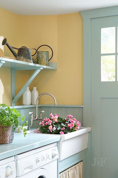 Turquoise mudroom features mustard yellow paint on upper walls and turquoise beadboard on lower walls lined with an enclosed washer and dryer as well as a white apron skirted sink under turquoise shelves. Yellow Mudroom, Blue Mudroom, Mustard Yellow Paint, Cottage Laundry, Beadboard Trim, Cottage Laundry Room, Yellow Laundry Rooms, Yellow Kitchen Walls, Stairs Hallway