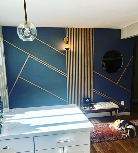 Wooden slats used as asymmetrical design on a blue grey painted wall in the entry way. Brass minimalist light fixture and a round brass mirror. Dark Blue Wall With Wood Accent, Navy Slat Wall, Blue Slat Wall, Slat Entryway, Blue Striped Walls, Wooden Panel Wall, Navy Accent Walls, Gold Accent Wall, Wall Wardrobe