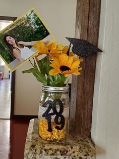 30 DIY Graduation Centerpieces That Are Easy, Cute, and Cheap Sunflower Graduation Centerpieces, Sunflower Table Centerpieces Mason Jars, Graduation Party Ideas Sunflowers, Graduation Sunflower Theme, Diy College Graduation Decorations, Sunflower Grad Party, Open House Centerpieces Grad Parties, Sunflower Graduation Party Ideas, Sunflower Themed Graduation Party