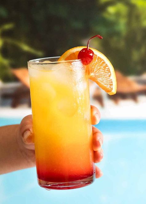 Hand holding Tequila Sunrise by a pool Tropical Sunrise Drink, Tequila Orange Juice, Tequila Sunrise Recipe, Tequila Sunrise Cocktail, Sunrise Cocktail, Maraschino Cherries, Best Tequila, Colorful Drinks, Recipetin Eats