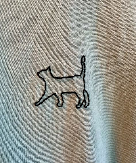 A cute black cat is hand embroidered onto a size Medium sage green Comfort Colors T Shirt. These T Shirts are famously comfortable and 100% cotton. They are machine washable and dryable. This piece is ready to ship next day. We are proud to offer free standard domestic shipping. You can upgrade to domestic priority when checking out. International shipping is estimated. Any overages will be refunded. To browse additional custom embroidery pieces, check out our shop's homepage at thepinandneedle.etsy.com Men’s Embroidery, Cute Embroidery Ideas Shirts, Cat Embroidery Simple, Embroidery Shirt Designs, Embroidery Animals, Embroidery Shirts, T Shirt Embroidery, Embroidered T Shirt, Embroidery Cute