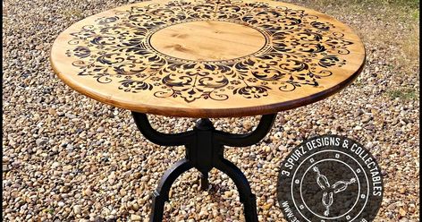 This gorgeous round table with a floral crown pattern heat transferred into the wood.      The three flowing shaped legs are the perfect co... Wrought Iron Patio Table, River Ideas, Diy Table Top, Crown Pattern, Into The Wood, Round End Table, Iron Stand, Wood Table Top, Diy Pattern