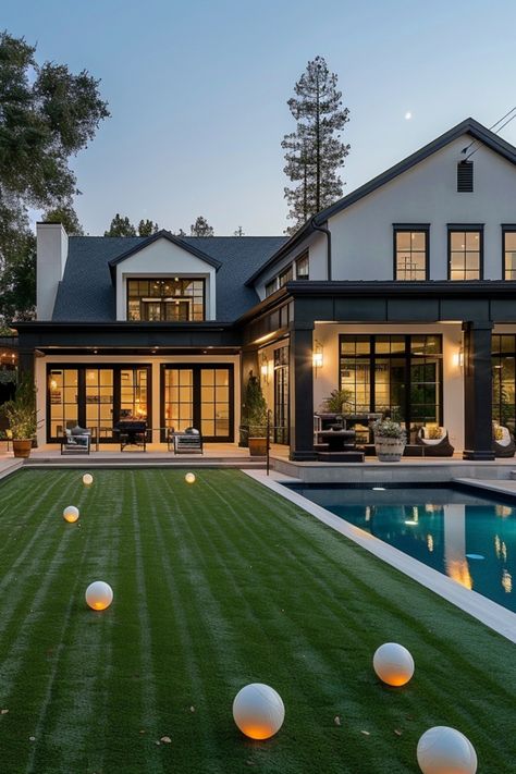 Modern house with large windows, a well-manicured lawn, and a swimming pool at dusk. Turf And Pool Backyard Ideas, Turf Grass Backyard Ideas, Large Grass Backyard Ideas, Small Luxury Backyard Ideas, Turf Backyard Ideas Landscaping, Turf And Pavers Backyard Pool, Fake Grass Backyard Ideas, White House Backyard, Turf In Backyard