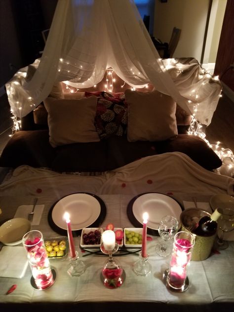 Make your indoor date night romantic!  You can use xmas lights to add to the ambiance along with comfy pillows! To create a fort you can use sheer curtains, they're lighter than sheets! Patio Date Night Ideas Romantic, At Home Date Night Setup Ideas, Romantic Night Decor, Living Room Dinner Date, Romantic Movie Date At Home, Indoor Date Setup, Date Night Fort Romantic, Vday Date At Home, Romantic Home Picnic Ideas