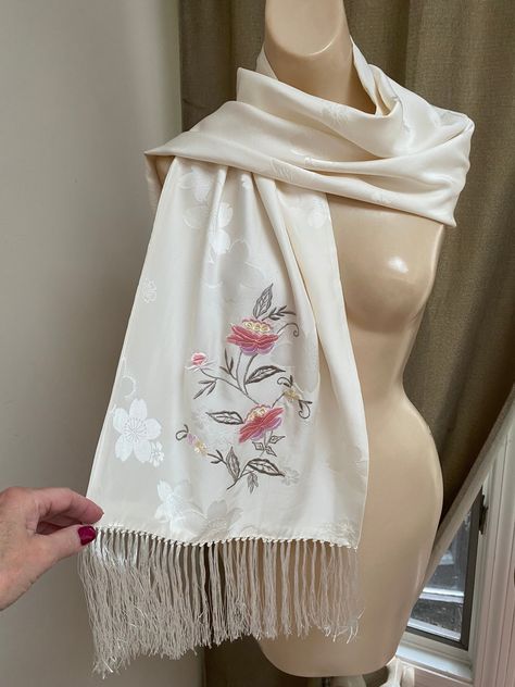 "Lovely embossed silk scarf/wrap in an ivory color with a flower embossed finish.   56\" length and 14\" wide - length doesn't include the 5\" silky fringe on either end.   I don't think this is long enough to wear as a shoulder wrap but more like a scarf as I've shown in the pictures. Pale cream beige color with a tiny sheen.   A large embroidered vine of flowers in shades of antique rose and sage on one end and a tiny single flower on the other end. Two layers of silk so no threads from the em Cream Beige Color, Embroidery Scarf, Silk Scarf Wrap, Embroidered Scarf, Shoulder Wrap, White Scarves, Ivory Silk, Birthday Board, Fringe Scarf